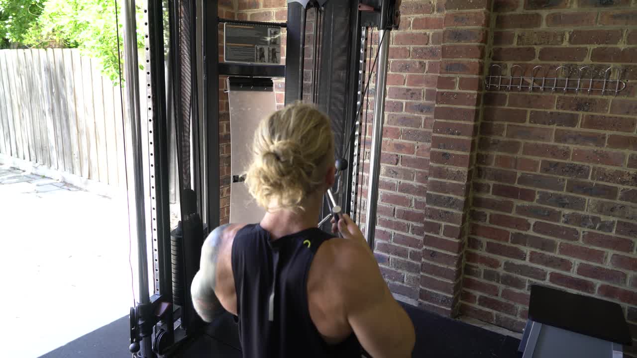 Tattoo man muscles in home gym doing cable lat rows rowing