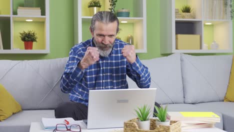 Mature-man-working-online-from-home-is-happy-with-the-event,-news-or-e-mail-he-sees-on-the-laptop.