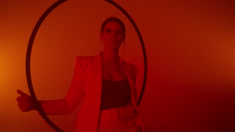woman in a white suit with a hoop in a red-lit studio