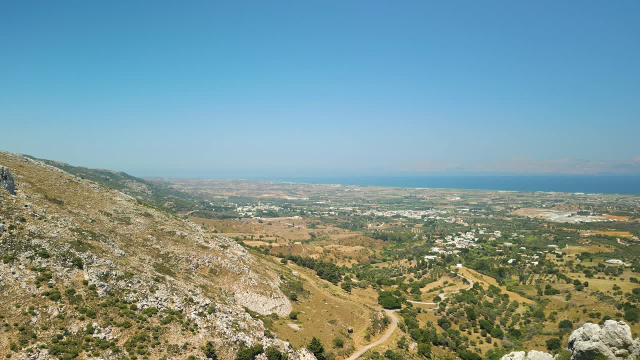 una vista de una ciudad remota a través del agujero en las montañas rocosas en kos, grecia