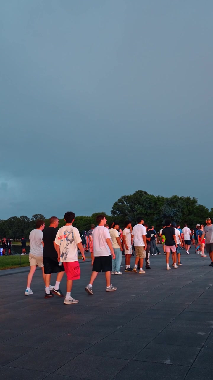 Washington, USA, 1 giugno 2026: folla di persone che cammina all'aperto su una piazza pavimentata. Giovani che indossano abiti con la bandiera americana camminano sotto un cielo scuro e coperto a Washington DC