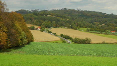 view of a twisted spiraling road along which cars and trucks run on the left side of a dense deciduous forest in strong wind with leaves shaking during a sunny day captured in beskids area 4k 60fps