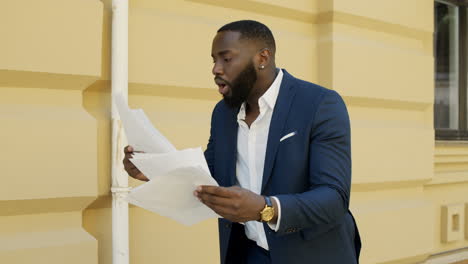 winner businessman walking outdoors. afro business man looking documents outside