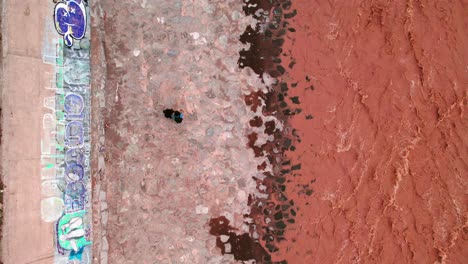 top view of a young couple walking synchronized on a path of large stones beside the brown mapocho river santiago chile