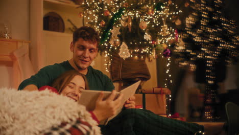 una pareja joven viendo un álbum de fotos en casa.