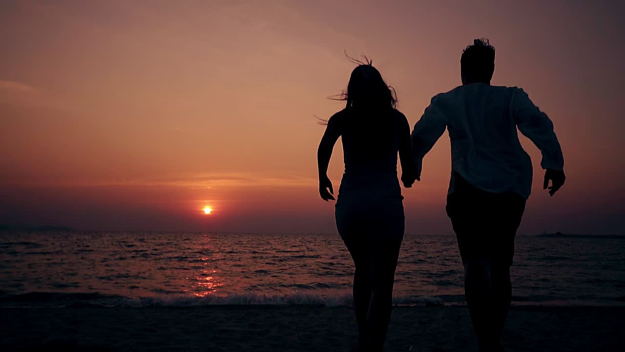 부부는 손을 잡고 해변에서 물로 달려갑니다.