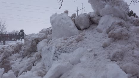grandes bancos de nieve altos al lado de la carretera en zona urbana en invierno