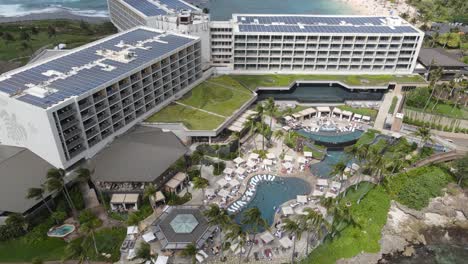 top-down aerial drone shot of a resort with people out by the pools near the turtle bay in oahu, hawaii