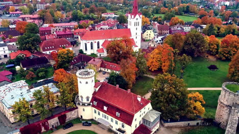 aerial drone shot over iconic medieval castle called cesis castle in latvia on a cloudy day with the view of the town in the background