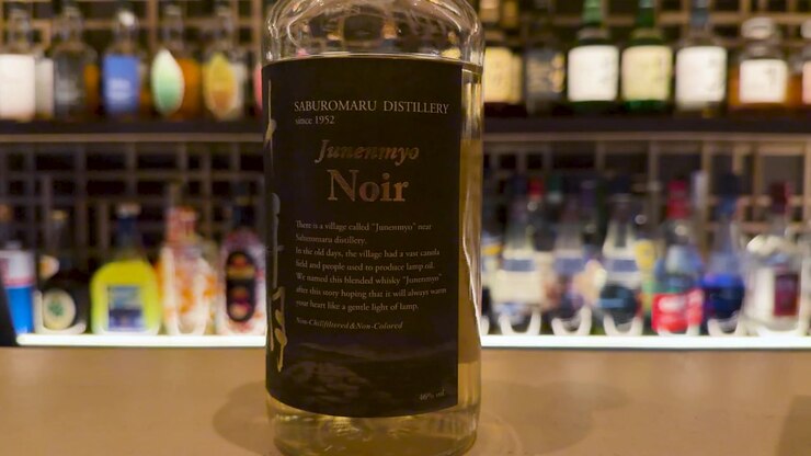 Primo piano di una bottiglia di whisky su un bancone da bar con sfondo sfocato a Kanazawa, Giappone