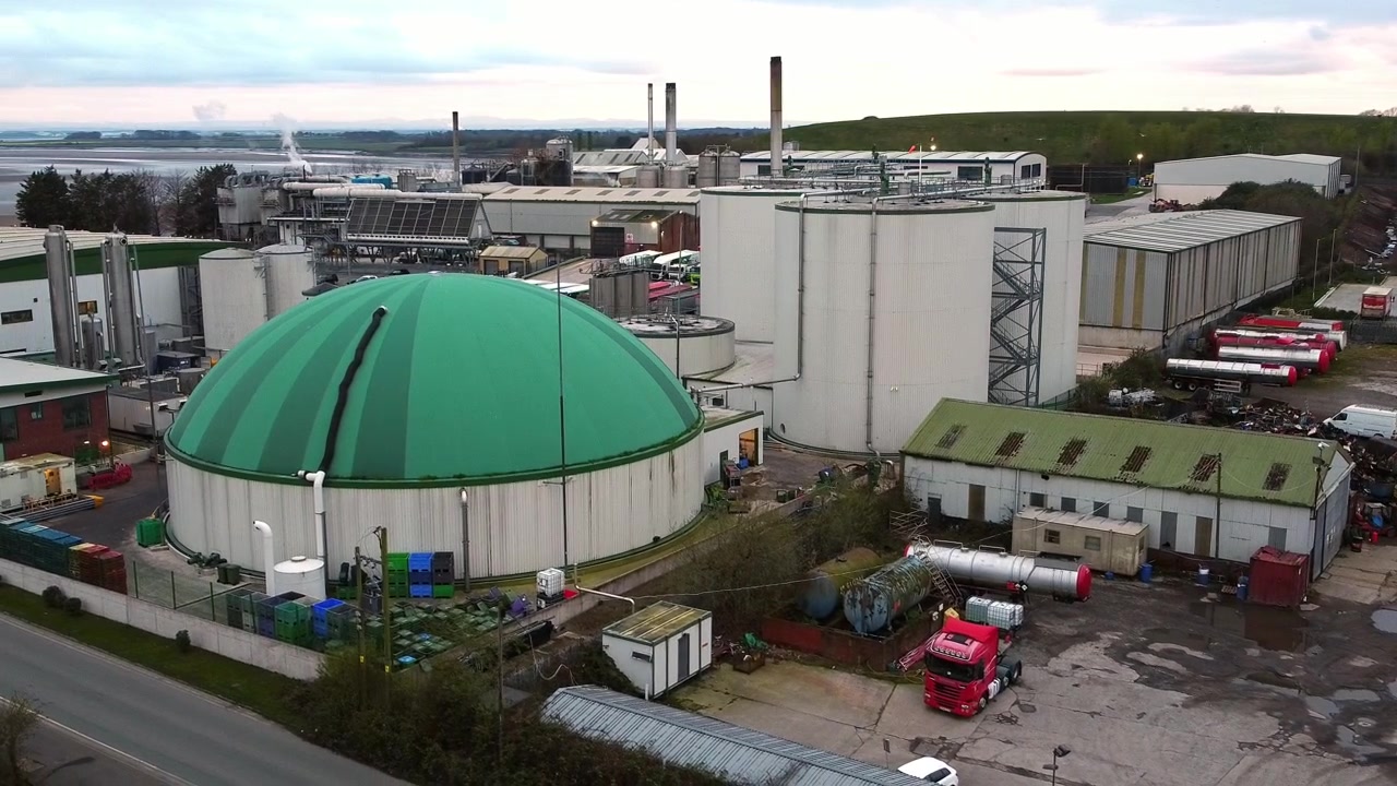 Vista aérea de una instalación industrial de silo de reciclaje biodegradable de residuos alimentarios con cúpula verde, en órbita descendente a la derecha