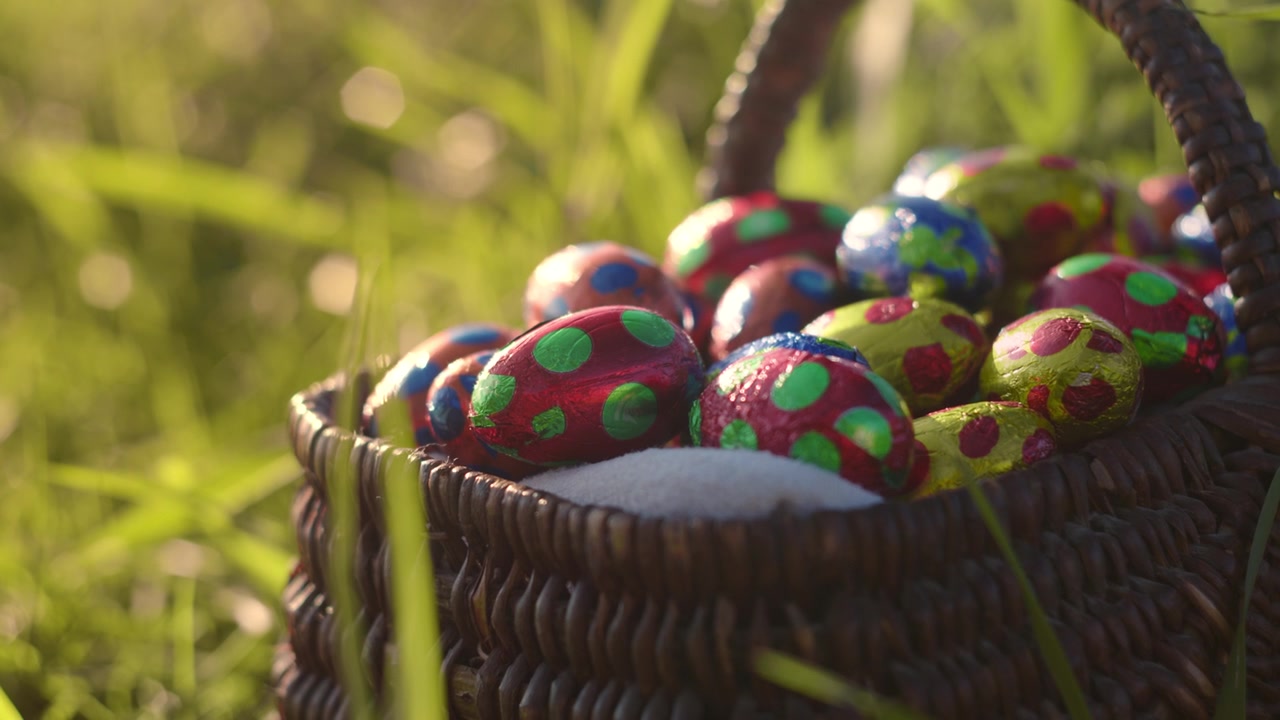 Colorful Chocolate Easter Eggs in a wicker basket. Garden Rack Focus