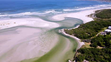 Picturesque-Klein-River-lagoon-breaching-over-sandy-beach-into-ocean,-drone-view