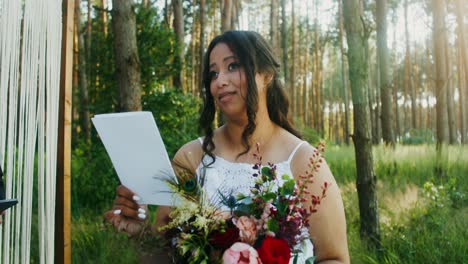 la novia leyendo los votos en la ceremonia de bodas en el bosque al aire libre