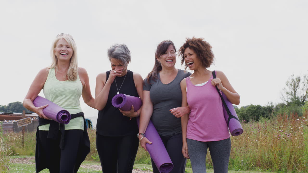 grupo de amigas maduras en un retiro de yoga al aire libre caminando por el camino a través del campamento