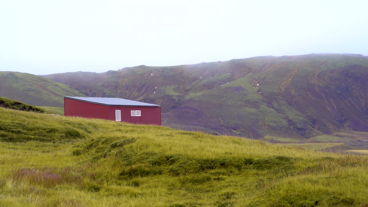 pintoresca cabaña roja solitaria, exuberantes campos verdes en las tierras altas de islandia