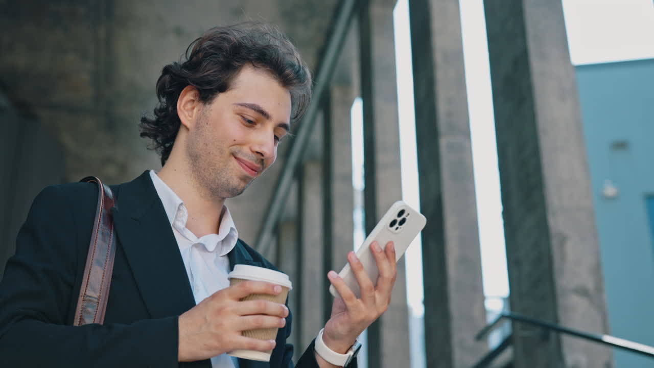 Young Businessman Drinks Coffee and Uses Smartphone in Urban Environment
