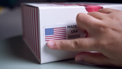 Hände-Bringen-Das-„Made-In-USA“-Flaggenetikett-Auf-Einem-Versandkarton-Mit-Produkten-An