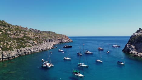 Anthony-Quinn-Bay-beach-in-Faliraki,-Rhodes-in-Greece-during-the-day-with-boats,-perfect-weather-for-summer-holiday-filmed-with-drone