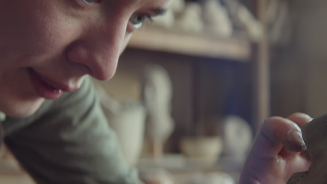 joven escultora que da forma a la cabeza de arcilla con una herramienta