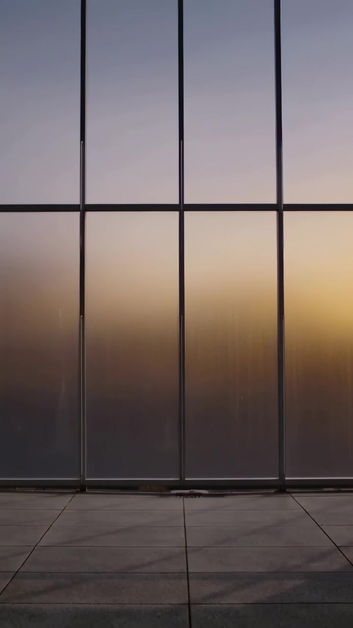 Vertical video: Shifting sunlight warming frosted glass wall in atrium, revealing metal mullions