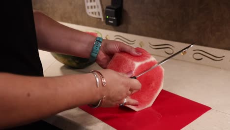 woman cuttings black diamond seedless watermelon into cubes