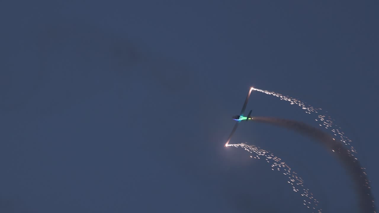 отслеживающий кадр пиротехнического самолета, выпускающего искры и факелы во время шоу