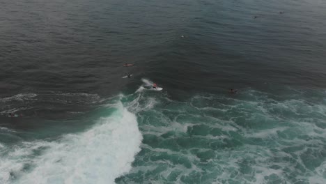 Top-down-view-of-people-wave-surfing-at-Bali-Indonesia,-aerial