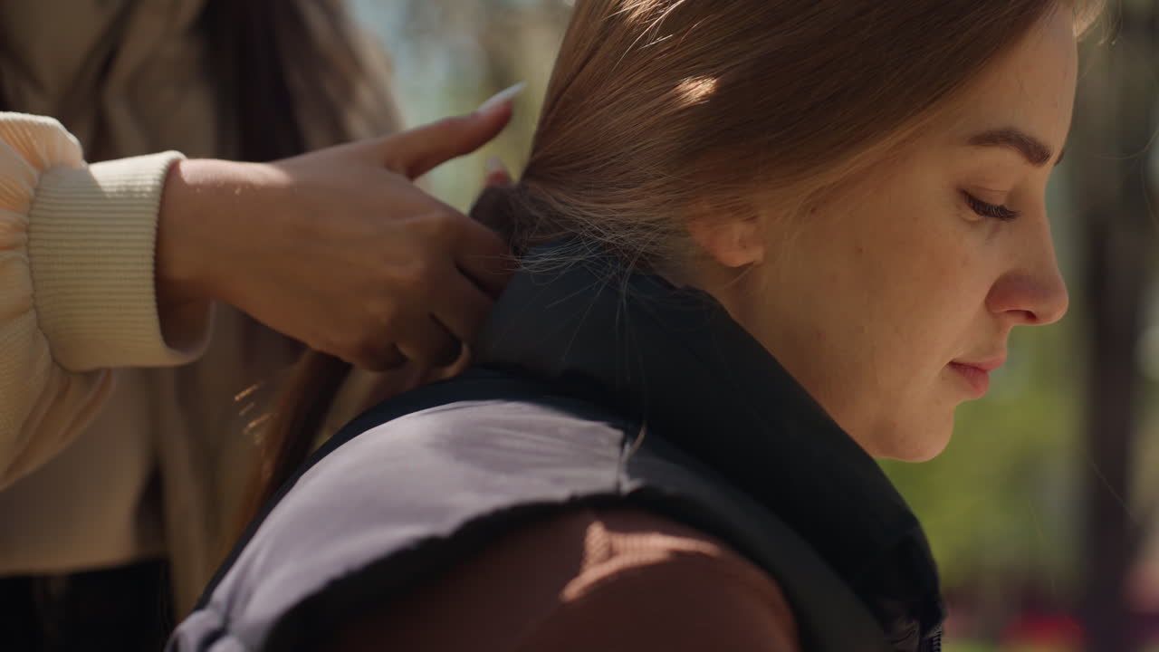 머리를 땋는 여성, 땋은 머리 스타일을 한 차분한 여성, 평화로운 공원 분위기 속에서 땋은 머리를 만드는 온화한 여성, 무성한 공원에서 차분한 표정으로 머리를 땋는 평온한 여성