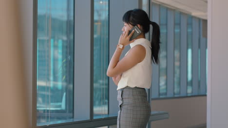 asian business woman using smartphone corporate sales executive chatting to client financial advisor negotiating deal sharing expert advice having phone call in office looking out window