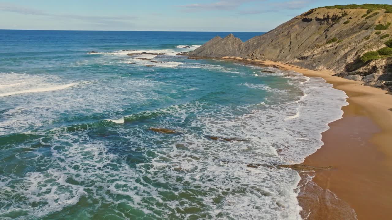 Aerial footage off the coastline of Portugal with its crystal clean ocean, rippling against its reef and rocks.
