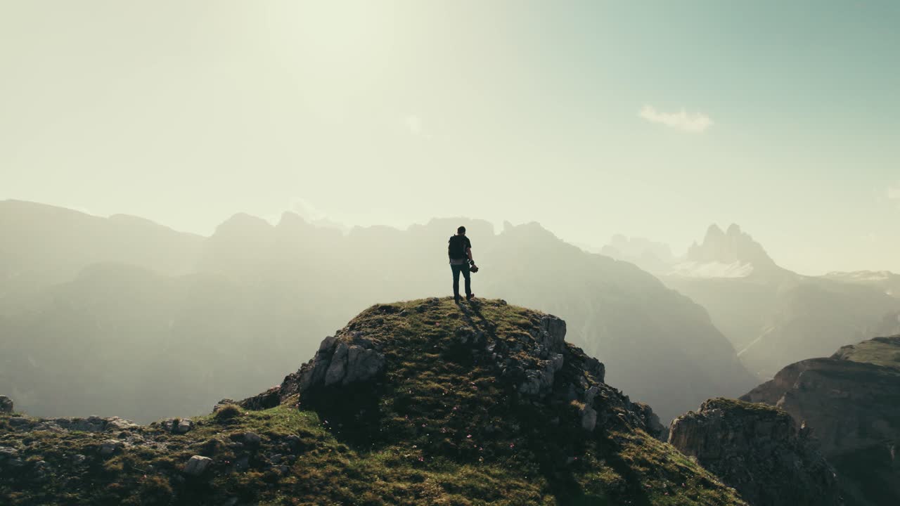 un excursionista masculino en una colina en las montañas durante el amanecer