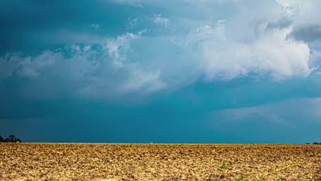 a time lapse shot of a blue sky and a wind shear above a golden dry field