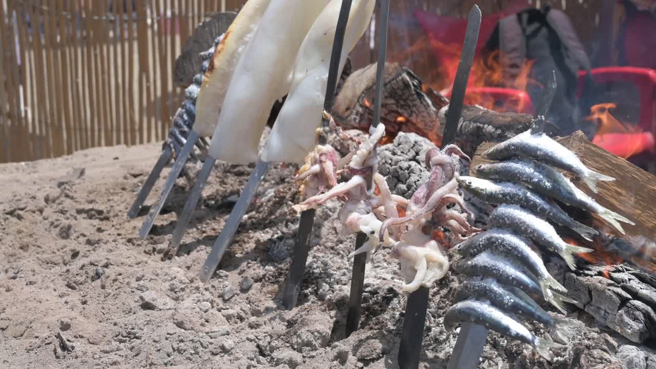 Sardines and fish grilling on a traditional espeto barbecue in Málaga on the beach