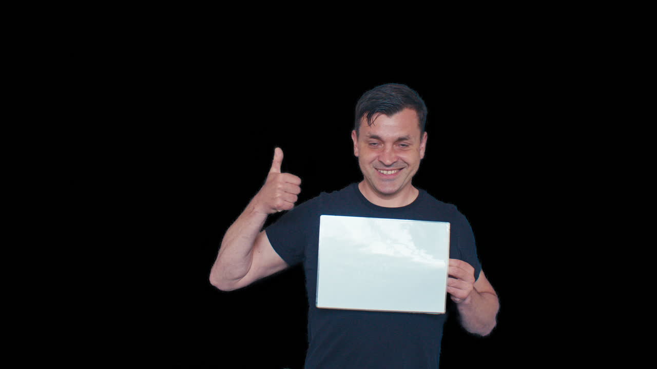 A male model man poses with white blank plate board sheet of paper and points at it with positive emotional reaction on black chromakey transparent removed no background