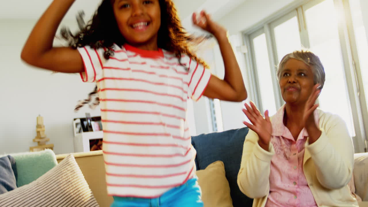 Grandmother applauding her granddaughter while dancing in living room 4k