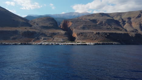 view from a moving boat of a mountainous and volcanic landscape of the cretan south coast