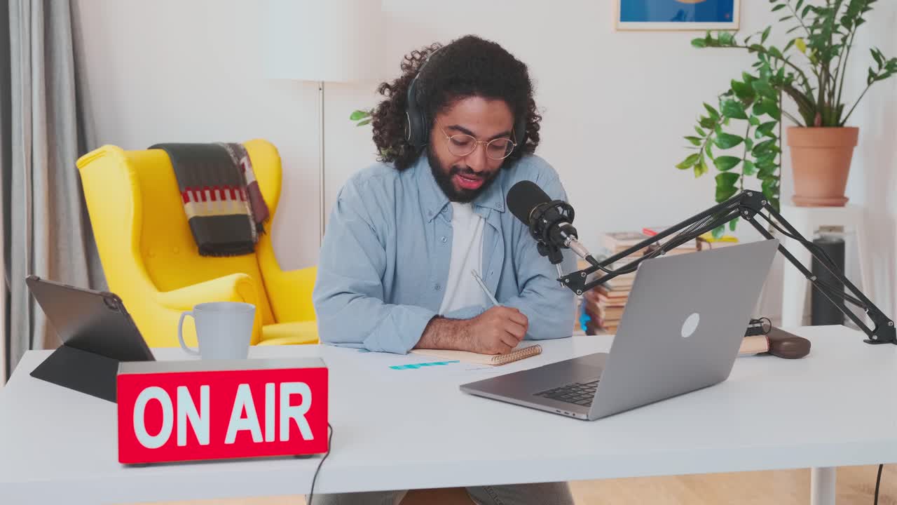 Young positive arabian man teacher of online school puts on headphones and talk