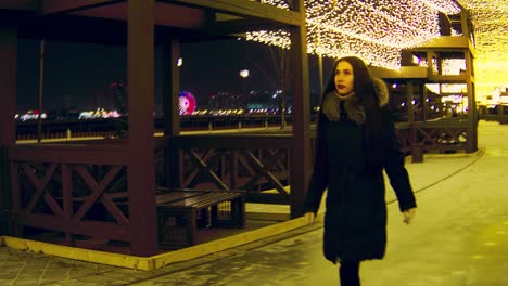 woman walking through a winter night city park with festive decorations