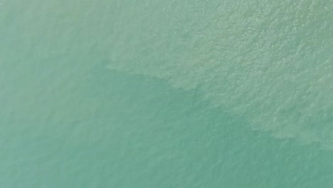 Birds-eye-shot-of-tranquil-clear-sea-water-toward-the-seaside-beach-from-Puerto-Galera-in-Mindoro,-Philippines