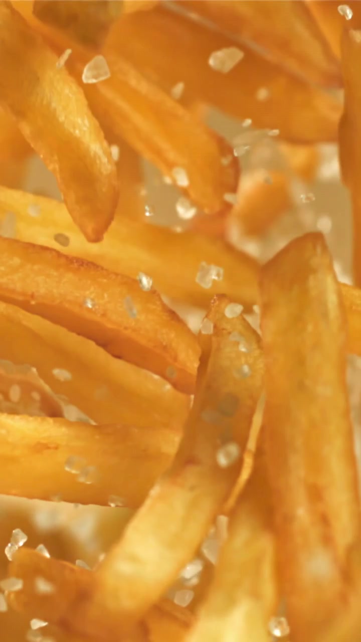 Golden French Fries Falling with Salt in Slow Motion
