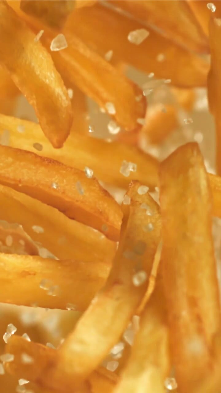 Golden French Fries Falling with Salt in Slow Motion