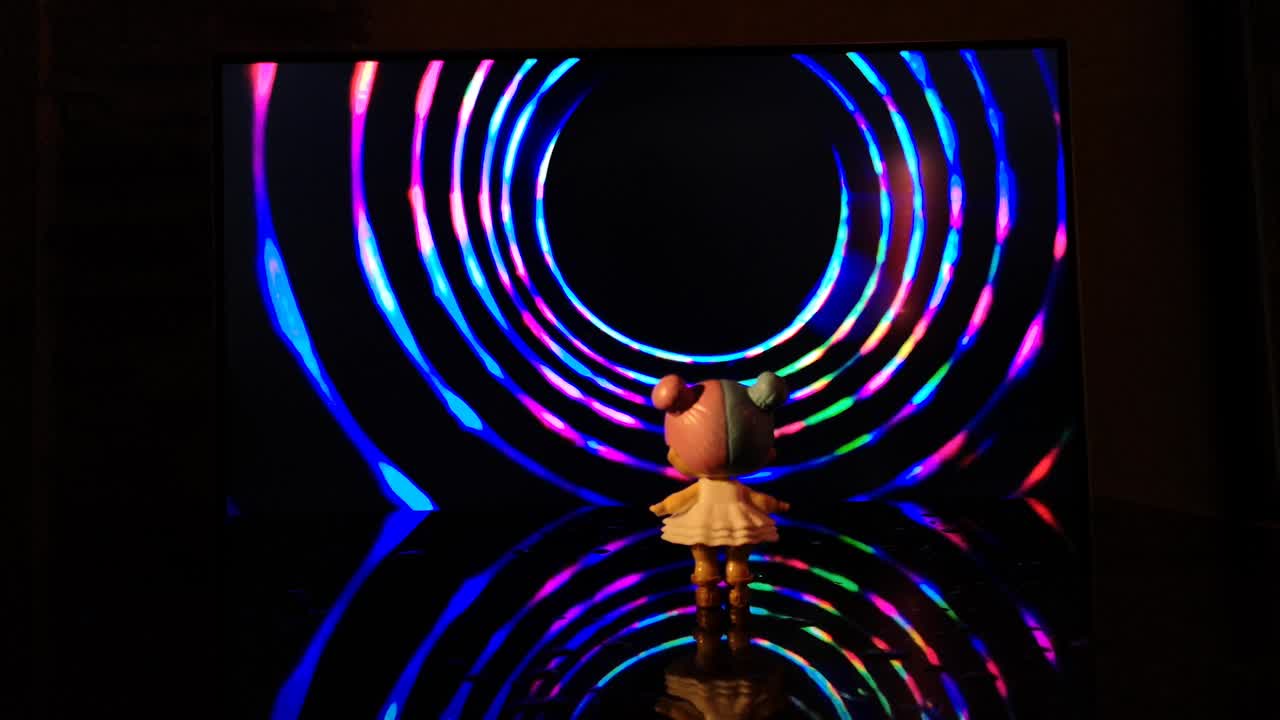 una niña pequeña está de pie frente a un embudo giratorio multicolor