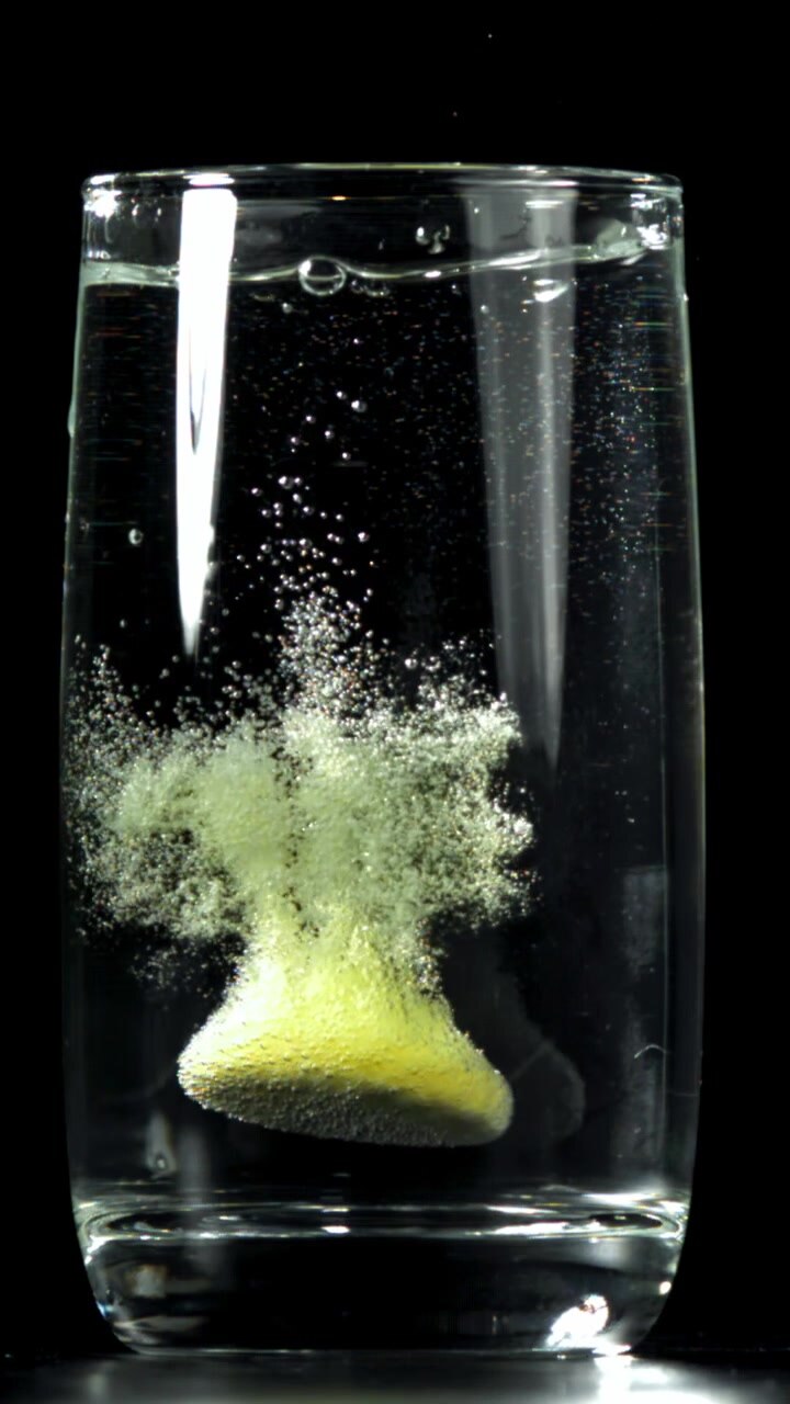 Compressa effervescente che si dissolve in un bicchiere d'acqua al rallentatore