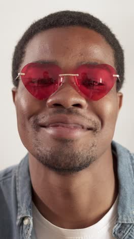 smiling man in red heart-shaped sunglasses
