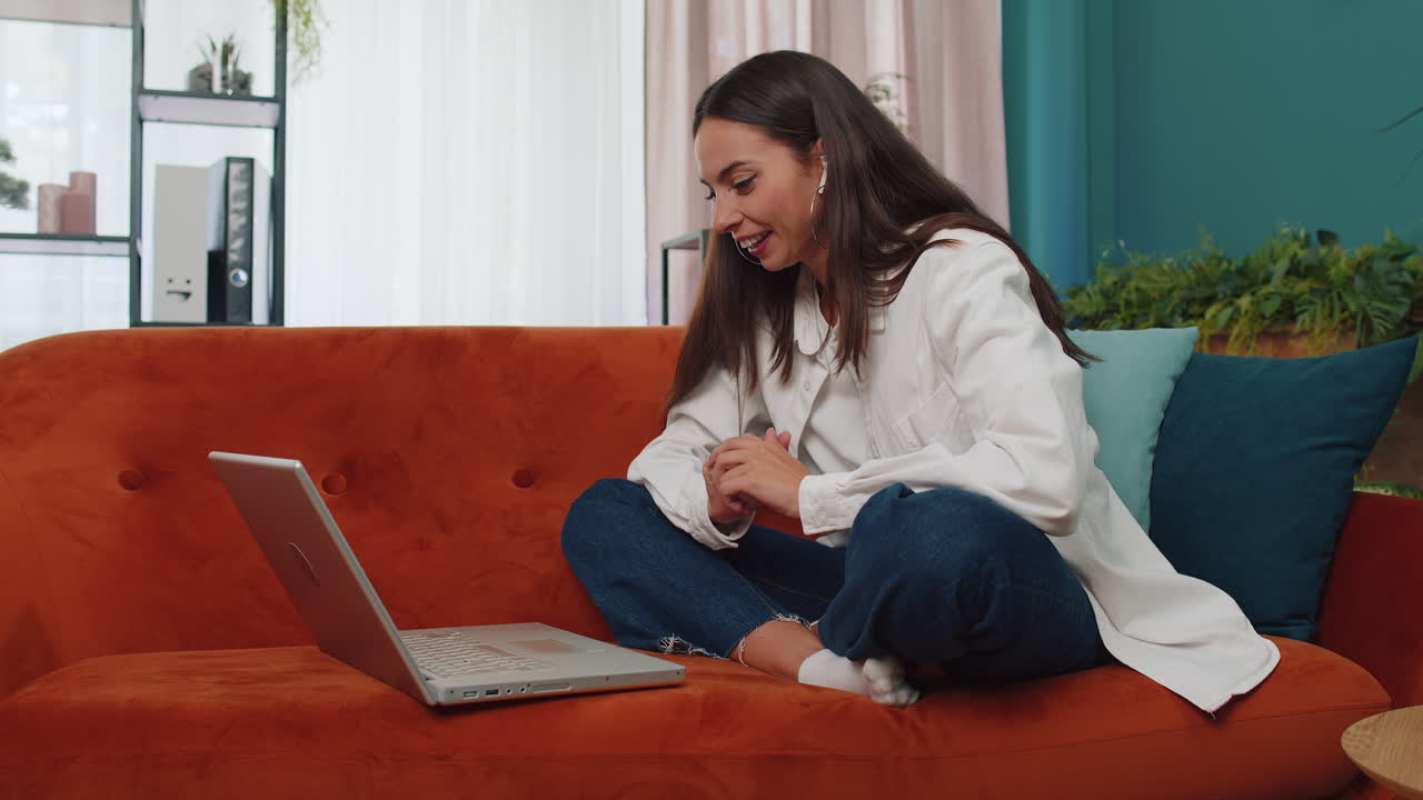 mujer sentada en el sofá de casa, mirando a la cámara, haciendo una llamada de videoconferencia con amigos o familiares
