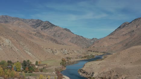 Drone-footage-following-a-backcountry-single-engine-plane-over-a-river,-surrounded-by-mountains,-and-landing-on-a-remote-landing-strip-in-the-Frank-Church-River-of-No-Return-Wilderness