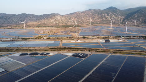 Windmill-turbine-electric-power-generation-in-scenic-salt-pond-field-with-natural-mountains-landscape-in-Asia-Vietnam