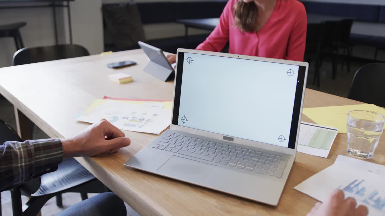 Laptop with copy space on screen and diverse colleagues in discussion in casual office, slow motion