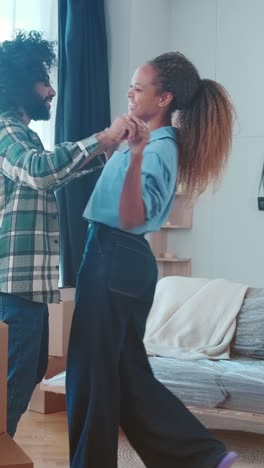 young positive multiethnic couple dance celebrating moving from old apartment